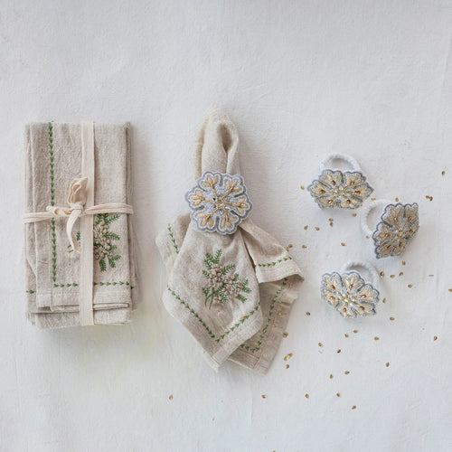 Cotton and linen embroidered napkins with French knots on table with napkin rings. 
