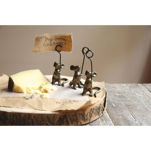 Three little cast iron mouse card holders styled on a cheese board. 