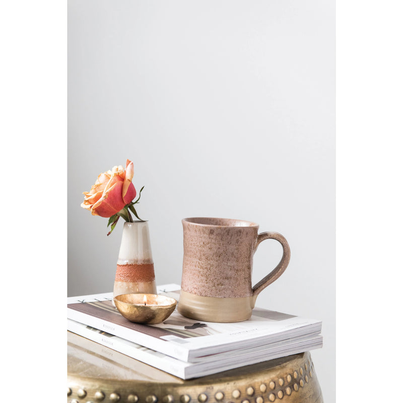 One stoneware mug styled with books and a flower in a vase. 