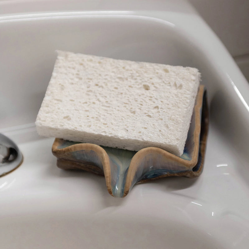 Stonware sponge holder with drip spout for drainage, pictured with a sponge sitting on dish