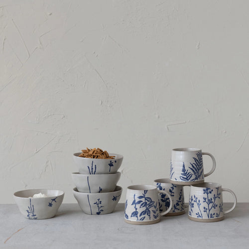 Antique white and blue hand stamped bowls and mugs on a table. 