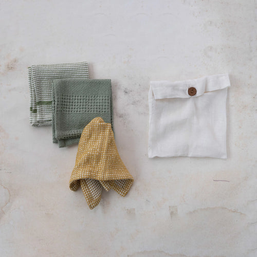 Three cotton waffle weave cloths folded beside their cotton storage bag. 