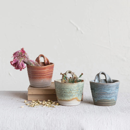 Three colors of stoneware wall planter with reactive glaze styled with dried flowers inside. 