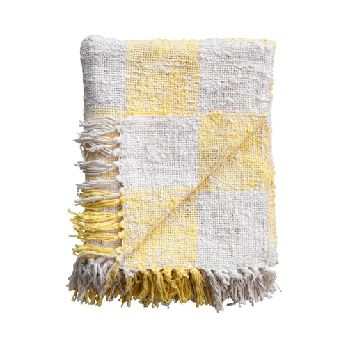 Folded yellow hand woven cotton throw blanket with fringe.