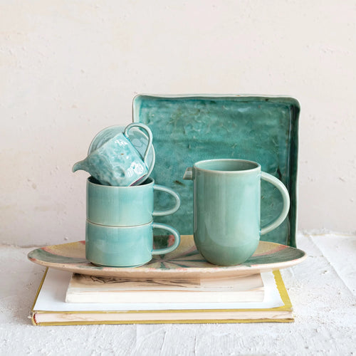 Aqua colored stoneware creamer styled with matching mugs and a platter. 
