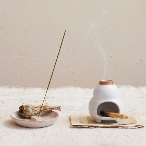 Stoneware incense holder holding an incense stick beside a different style incense holder.
