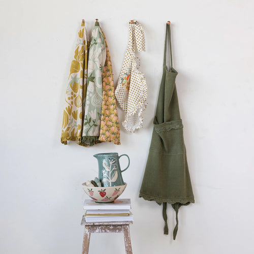 Cotton printed half apron hanging on the wall with printed tea towels.
