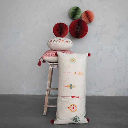 Embroidered pillow stacked on top of a distressed wood stool.