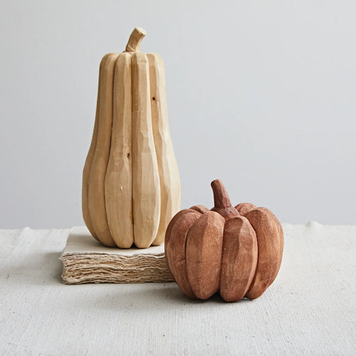 Hand carved natural wooden pumpkins on tabletop. 
