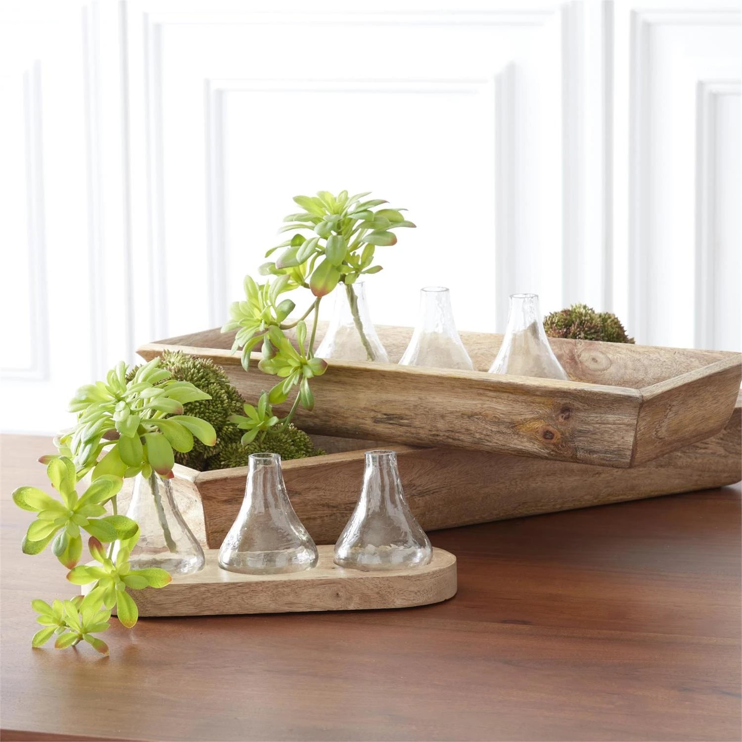 Green sedum balls displayed in natural wood dough bowls on a kitchen table. 