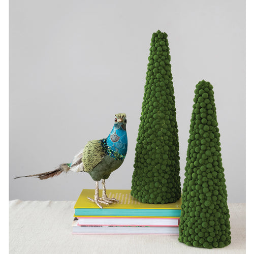 Two green flocked foam ball trees on top of a stack of books with a hand crafted peacock.