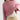 A close-up of a person wearing a dusty pink ribbed knit cropped sweatshirt over a white textured top, paired with beige drawstring cargo pants and a beaded necklace.