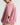 A woman wearing an oversized dusty pink ribbed sweatshirt, shown from a side-back angle against a plain light gray studio background.