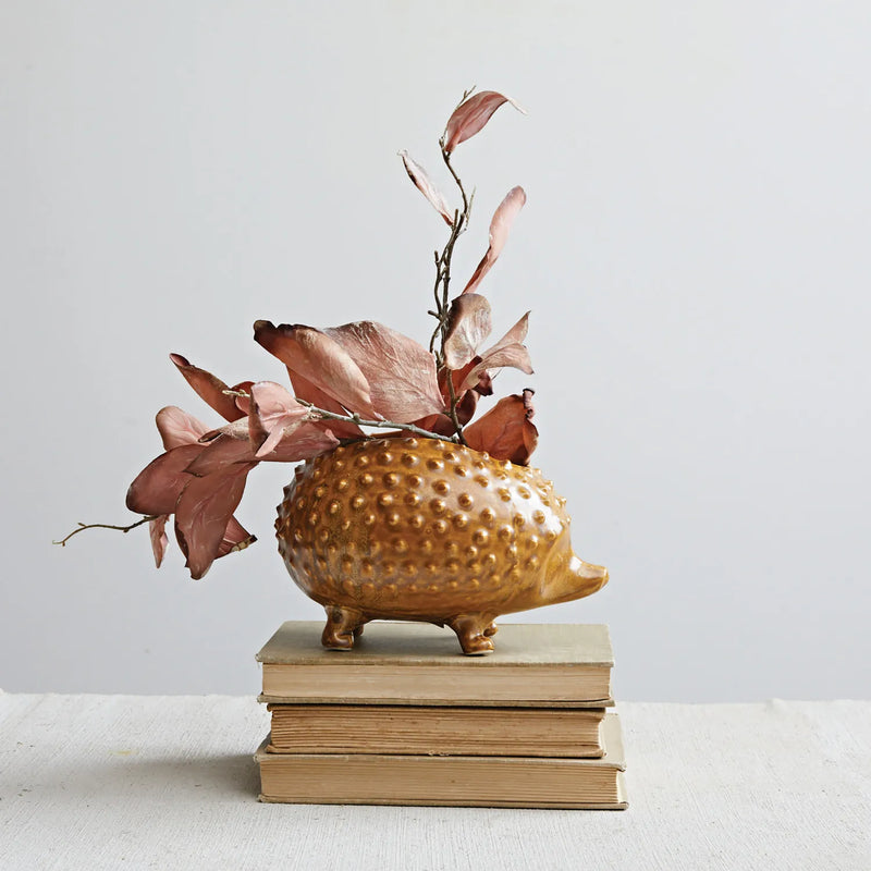 Hedgehog planter with leaves sitting on top of a stack of books. 