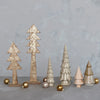 Stoneware and wood trees styled on a tabletop with metallic ball ornaments and glitter. 