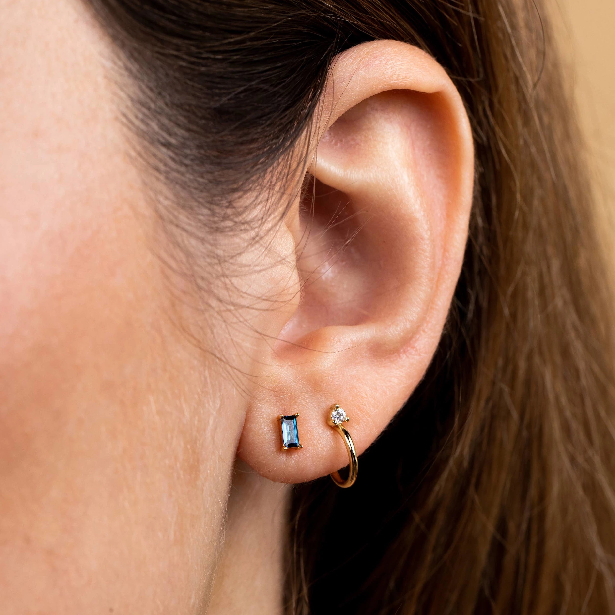 Model wearing JaxKelly baguette earrings in the color sapphire.