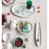 Elegant oval debossed stoneware tray styled with various holiday themed dishes and decorations.