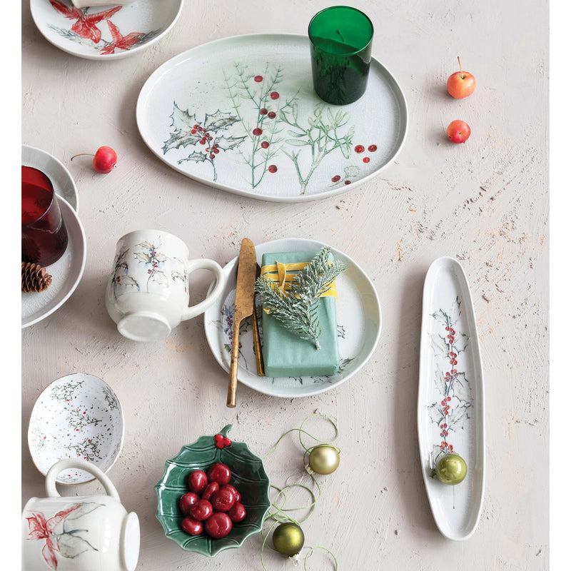 Elegant oval debossed stoneware tray styled with various holiday themed dishes and decorations.