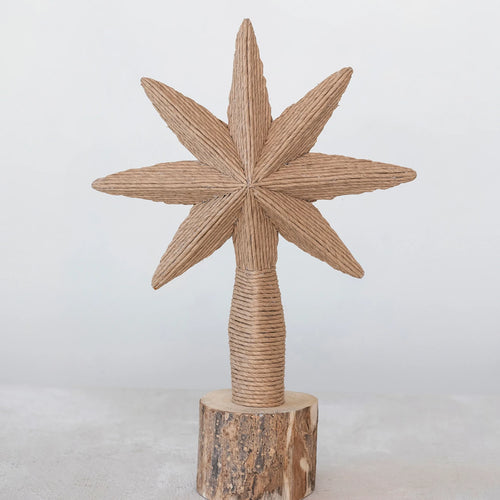 Unique handmade paper and twine star tree topper on a wooden stump.