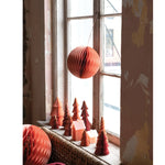 Paper honeycomb ornaments in window with paper trees and house candles in winow sill. 