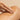Hand applying a brown lotion or oil to a person's leg on a beige background