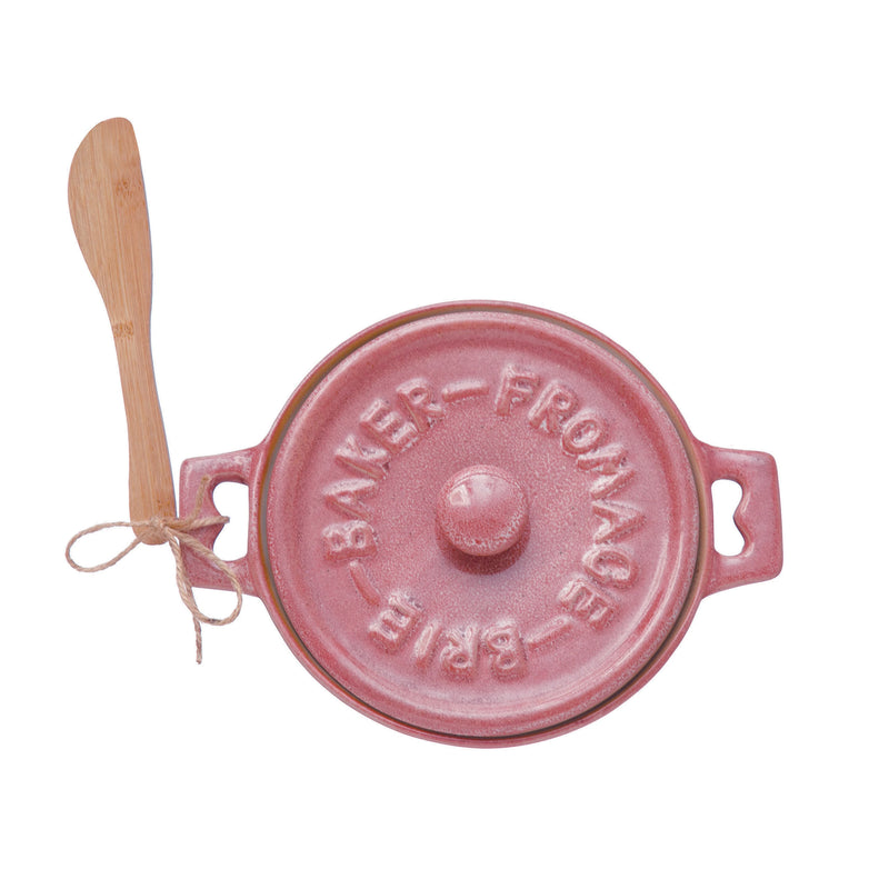 Stoneware brie baker in the color pink with a wooden bamboo spreader.