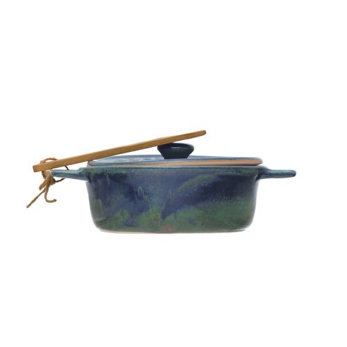 Side view of the glazed dark blue stoneware brie baker with bamboo spreader.