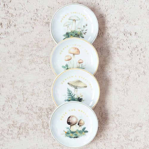 Four round stoneware dishes with mushroom image and holiday greeting. Elegant gold and green electroplating detailing around the dish.