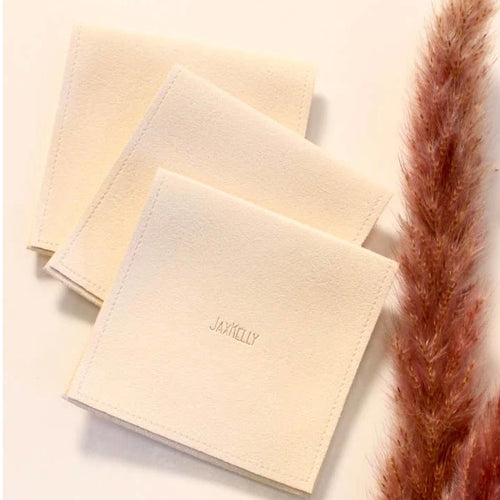 JaxKelly suede-feel jewelry pouch in a cream color styled with some pampas grass.