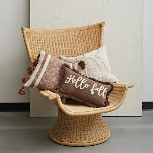 Tufted Pumpkin pillow on wicker chair with other pillows.