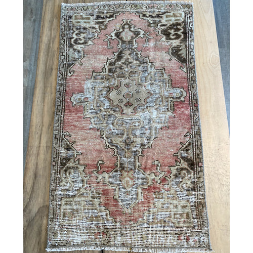 Heavily distressed Turkish area rug in pink, brown and beige.