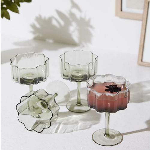 Set of 4 stemmed champagne coupe glasses with cocktails.