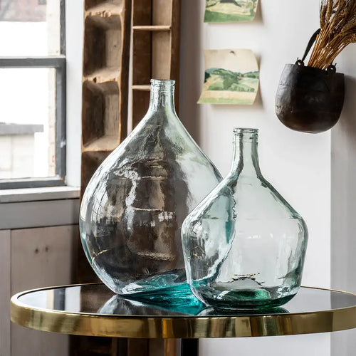 Vintage glass bottles sitting on top of a round marble and brasstable. 