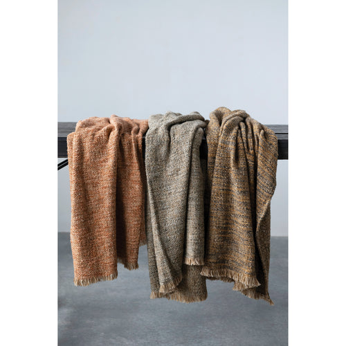 Cozy cotton and boucle throws tossed over a rustic bench. 