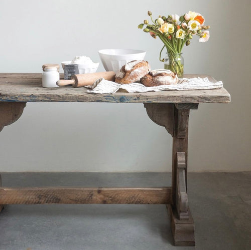 Reclaimed wood dining table with fresh bread and flowers ontop. 